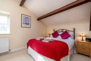 a bedroom with a large bed with a red blanket at Tregarnedd Cottage in Llangefni