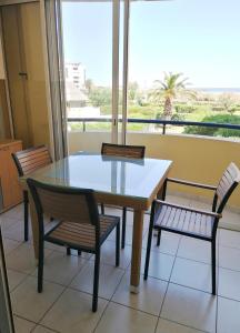 stół i krzesła w pokoju z oknem w obiekcie SAVANNA BEACH I Joli T2 avec vue mer piscine Cap d'Agde w Cap d'Agde +2 zdjęcia
