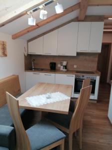 une cuisine avec des placards blancs et une table et des chaises en bois dans l'établissement Gspoi-Hof, à Laion