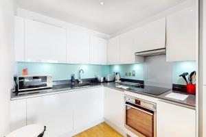 a white kitchen with white cabinets and a microwave at Lovely 1 bed apartment in Streatham in London