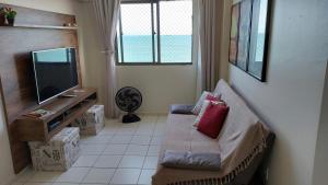 ein Wohnzimmer mit einem Sofa und einem Flachbild-TV in der Unterkunft Apartamento com 2 quartos de FRENTE PARA O MAR in Maceió