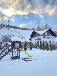 a playground in the snow with skis and a house at Casa Violetei in Bran