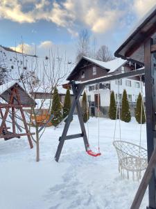 a swing set in the snow in a yard at Casa Violetei in Bran