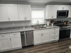 a kitchen with white cabinets and a stainless steel dishwasher at Coastal Getaway in Morehead City