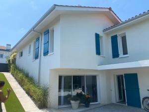 un homme debout devant une maison blanche dans l'établissement Agréable T2 près des plages avec parking, à Arcangues