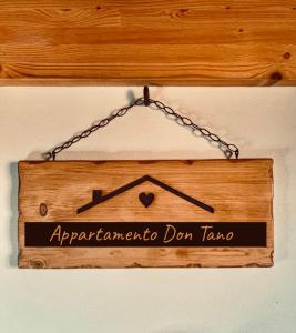 un cartello di legno appeso a una catena su un muro di Appartamento Don Tano a Catania