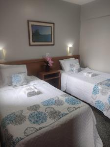 um quarto de hotel com duas camas e uma foto na parede em FLAT ECONÔMICO E ACONCHEGANTE, 1Qt, sala e cozinha, Centro-GO em Goiânia