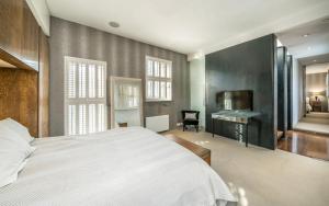 a bedroom with a bed and a desk and a television at Unique,architecturally acclaimed,Notting Hill home in London