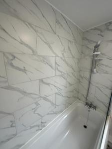 y baño con bañera blanca y paredes de mármol. en 3 Bedroom House For Corporate Stays in Kettering en Kettering