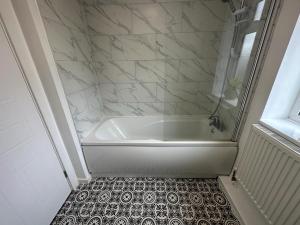 y baño con bañera blanca y suelo de baldosa. en 3 Bedroom House For Corporate Stays in Kettering en Kettering