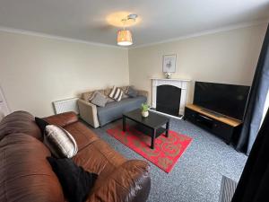 a living room with a couch and a flat screen tv at 3 Bedroom House For Corporate Stays in Kettering in Kettering