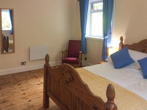 a bedroom with a bed and a chair and a window at Druimbhan, 1 Railway Cottage, in Lochailort