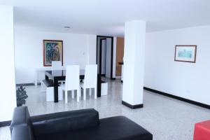 uma sala de estar com um sofá preto e cadeiras brancas em Eslait Hotel & Apartamentos em Barranquilla
