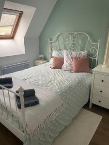 a bedroom with a white bed with pink pillows at Cocon douillet en bord de mer in Grandcamp-Maisy