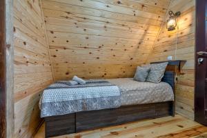 a bed in a log cabin with a wooden wall at Vila Deniri in Zlatibor