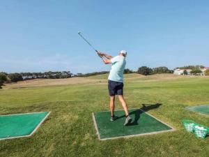 een man zwaaiend met een golfclub op een golfbaan bij Appartement vue Port Bourgenay, emplacement idéal in Talmont