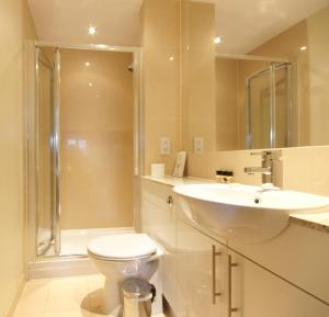 y baño con aseo, lavabo y ducha. en Lodge Drive Serviced Apartments en Enfield