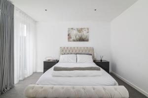 een witte slaapkamer met een groot bed met witte lakens bij Luxury Spacious Flat with Communal Gardens and Parking in Londen