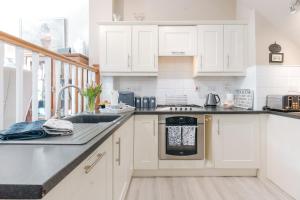 a kitchen with white cabinets and a sink at Ironbridge View Townhouse - Stunning view of the Iron Bridge UK WINNER 2024 'MOST PICTURESQUE SELF-CATERING HOLIDAY HOME' of the year' & WINNER '2024 BEST HOLIDAY HOME IN SHROPSHIRE' in Ironbridge