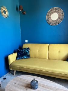 um sofá amarelo num quarto azul com uma ventoinha em Maison d'hôtes Bastide St Victor à 2,5 kilomètres de Lourmarin em Puyvert