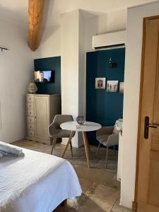 um quarto com uma cama, uma mesa e uma televisão em Maison d'hôtes Bastide St Victor à 2,5 kilomètres de Lourmarin em Puyvert