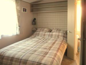 a bed with a plaid blanket in a bedroom at Windy Roost Lodge in Tydd Saint Giles