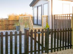 a wooden fence in front of a house at Windy Roost Lodge in Tydd Saint Giles