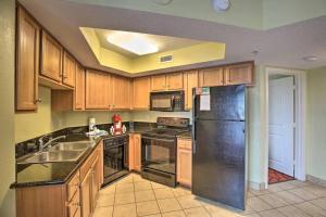 a kitchen with wooden cabinets and a black refrigerator at Bayview Resort Penthouse w/ Sunset Views in Myrtle Beach