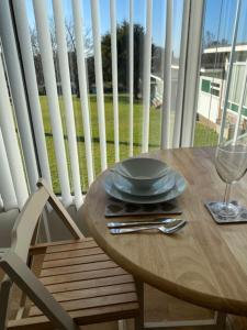 a wooden table with a glass of wine and a chair at The View. Stylish modern Chalet in great location. in Cromer