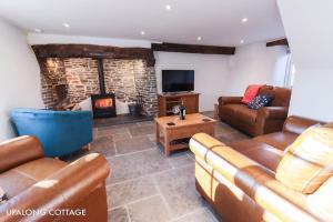 sala de estar con muebles de cuero y chimenea en UpAlong Cottage - HiddenDevon en Winkleigh