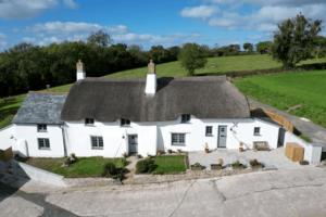 a large white house with a thatched roof at UpAlong Cottage - HiddenDevon in Winkleigh