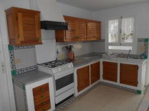 una cocina con electrodomésticos blancos y armarios de madera en Villa meublée à skanes Monastir en Monastir