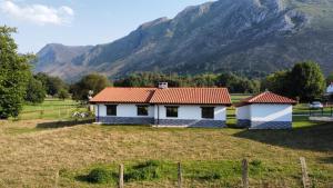 a house in a field with mountains in the background at El Llagar de Mon II in Llanes