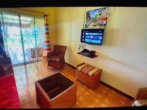 Elle comprend un salon avec des chaises en osier et une télévision murale. dans l'établissement Casa La Playa - # Sea,Sun & Relax #, à Riambel