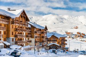 a lodge in the snow with snow covered mountains at Résidence Lagrange Vacances Les Hauts de Comborcière in La Toussuire