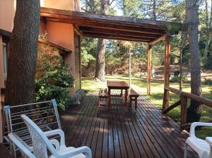 una terraza de madera con mesa y sillas. en Las Nenas. Un paraíso en el bosque en Balneario Mar Azul