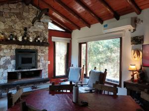 sala de estar con sillas y chimenea de piedra en Las Nenas. Un paraíso en el bosque en Balneario Mar Azul