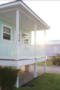 a small green house with a white deck at Key West Cottages in Chincoteague