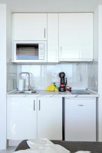 a white kitchen with a sink and a microwave at SEA LA VIE Ponderosa 617 in Playa Fañabe