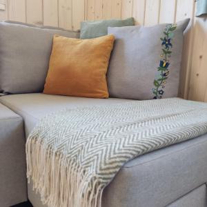 a gray couch with a throw blanket on it at Domek z balią in Chmielno