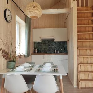 a kitchen with a white table and white chairs at Domek z balią in Chmielno