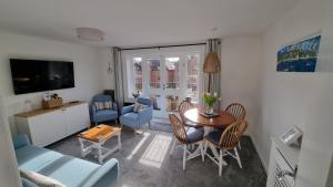 uma sala de estar com uma mesa e cadeiras e uma televisão em HighTide - 2 bed with parking, balcony & sea view. em Swanage