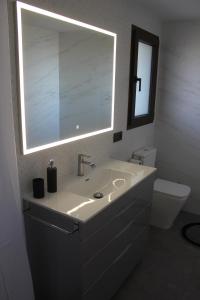 a bathroom with a sink and a mirror and a toilet at CASA RURAL MENSIN in Vilar de Canes
