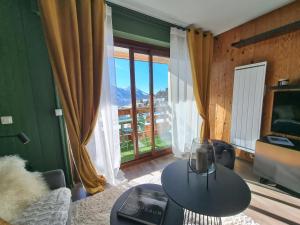 a living room with a table and a large window at STUDIO - ROCHES ROUSSES b in Orcières
