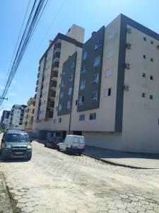 a parking lot with cars parked in front of buildings at Apartamento no Mar Grosso em Laguna SC. in Laguna