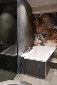 a bathroom with a bath tub and a white sink at Aiola Living Graz in Graz