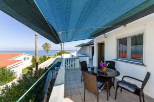 eine Terrasse mit einem Tisch, Stühlen und einem blauen Sonnenschirm in der Unterkunft Apartments Elvir Nin in Nin