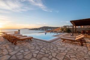 a pool with lounge chairs and a view of the ocean at Salty View in Mikonos