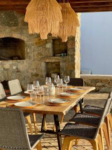 a wooden table with glasses and plates and chairs at Salty View in Mikonos