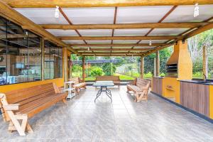 patio con bancos, mesa y fogones en Rosa Casa Várzea Grande, en Gramado